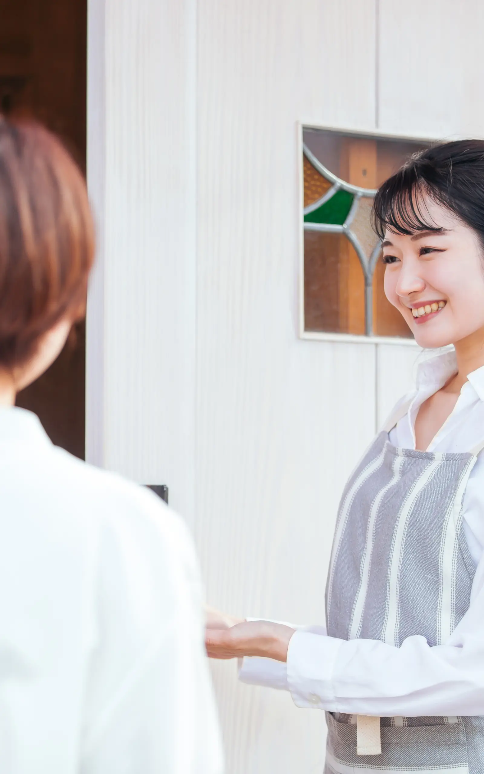 笑顔でお客様を迎え入れているカフェ店長のイメージ